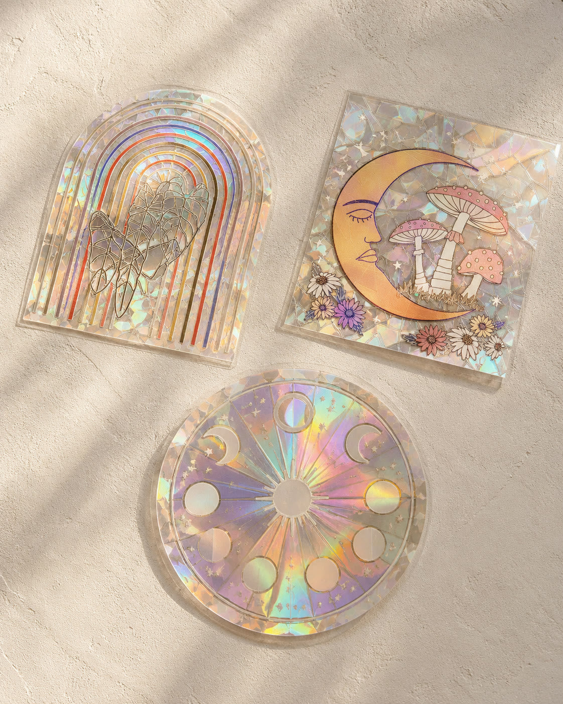 Three Glimmerprism suncatcher stickers laid out in afternoon sunlight