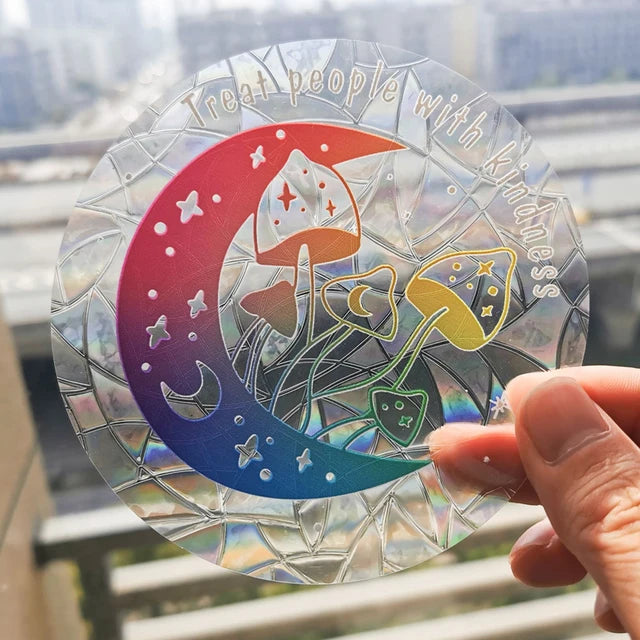 Kindness Moon suncatcher sticker held to the light